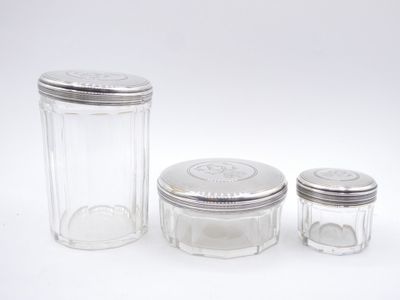 three glass jars with silver lids on a white surface