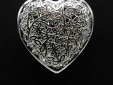 a close up of a silver heart shaped pendant on a black background