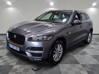 un SUV Jaguar gris garé sur un sol à damier dans un garage