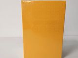 un livre orange posé sur une table blanche, près d'un mur blanc