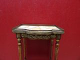 a small table with a marble top in front of a red wall