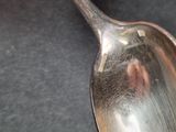 a silver spoon with a silver handle on a black surface