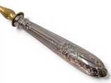 an antique silver and gold spoon with a gold handle on a white background