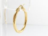 a close up of a pair of gold hoop earrings on a clear stand