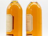 two bottles of wine sitting next to each other on a white surface