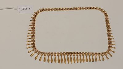 gros plan d'un collier en or sur une surface blanche