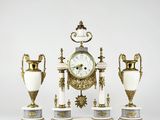 three vases and a clock sitting on a table
