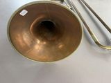 a brass trombone with a brass handle on a white table
