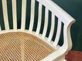 an image of a white bench with wicker seat in front of a green wall