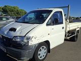 un camion blanc endommagé, garé sur un parking