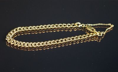 gros plan d'un bracelet en chaîne en or sur une surface noire
