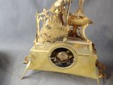 a gold clock with a woman sitting on a bench