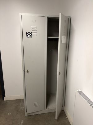 un casier métallique dans un coin de la pièce, à côté d'un radiateur