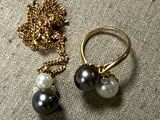 two rings with pearls and a gold chain on a table