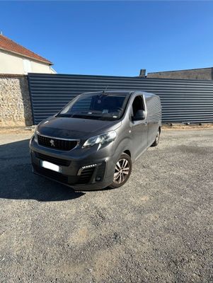 une camionnette grise garée sur un parking à côté d'un immeuble