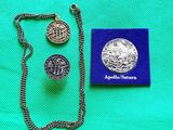 un collier en argent et une pièce d'argent posés sur un tissu vert