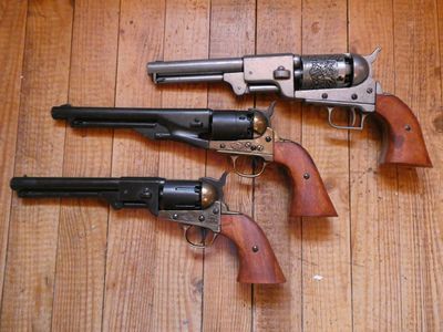 trois vieux revolvers posés côte à côte sur un plancher en bois