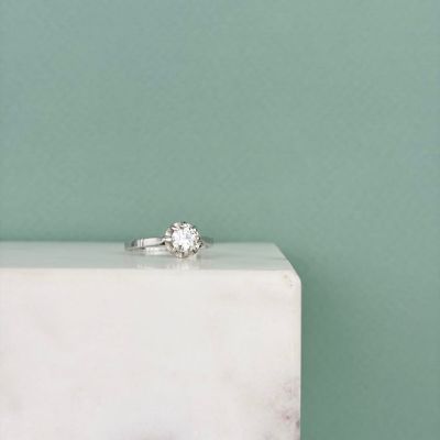 une bague en diamant posée sur un bloc de marbre blanc