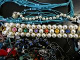many necklaces and bracelets laid out on a table