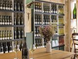 bottles of wine and glasses on a table in front of a wall of wine bottles