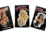 trois albums de bandes dessinées érotiques sont alignés sur une surface blanche