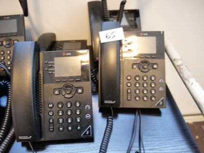 Plusieurs téléphones sont alignés sur une table bleue, accompagnés d'une étiquette de prix