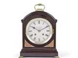 une petite horloge en bois avec des chiffres romains sur le cadran