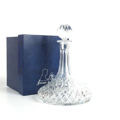 un flacon de parfum en verre posé devant une boîte bleue