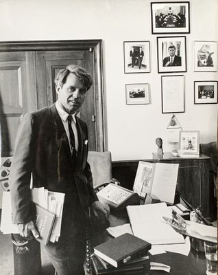 photographie en noir et blanc d'un homme en costume debout dans un bureau