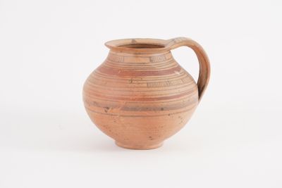 a brown vase with a handle on a white surface