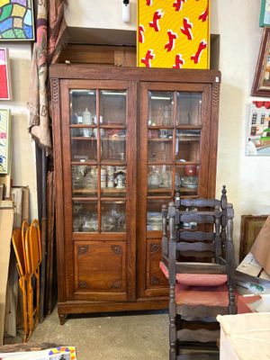 a wooden cabinet with a glass door and a chair in front of it