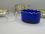 un saladier en verre bleu posé sur une table à côté d'autres saladiers en verre