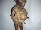 une vieille statue en bois représentant un homme coiffé d'un chapeau et tenant une balle