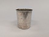 an old silver cup sitting on top of a white table