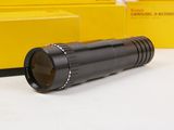 a black flashlight sitting on a table next to a yellow box