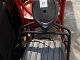 yellow and black lawn mower sitting on top of a pile of red chairs