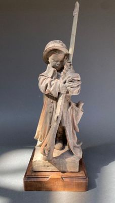 statue d'un homme tenant une épée, posée sur un socle en bois