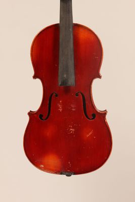 an old violin hanging from a string on a white wall