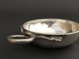 a silver bowl with a spoon in it on a black surface