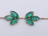 a close up of a bracelet with green stones on it