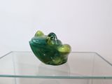 a green frog figurine sitting on top of a glass table