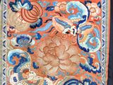 a close up of an orange and blue embroidered cloth with flowers on it