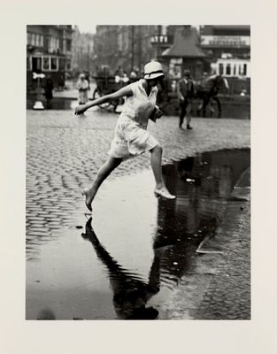 black and white photograph of a woman swinging a baseball bat on a wet street