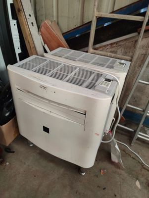 a white air conditioner sitting next to a pile of junk
