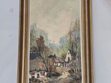 painting of a farm scene in a gold frame on a glass table