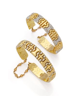 un gros plan sur deux bracelets en or sur fond blanc
