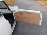 a white car with its door open sitting on the side of the road