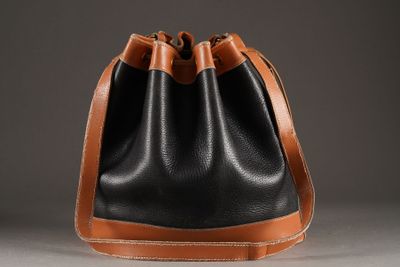 black and tan leather bucket bag on grey background