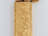 gold lighter on a white surface with a lighter in the middle