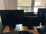 three monitors sitting on a desk in front of a window